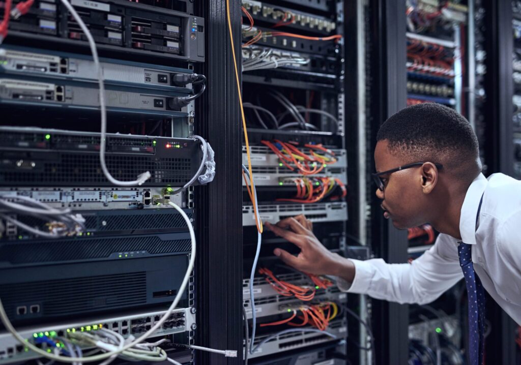 black man it technician server room cyber security data network storage inspection african male person networking administrator checking system cables installation datacenter