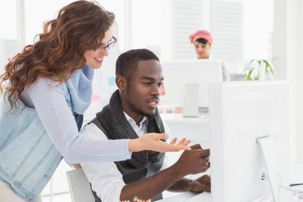 smiling coworkers interacting and using computer in the office